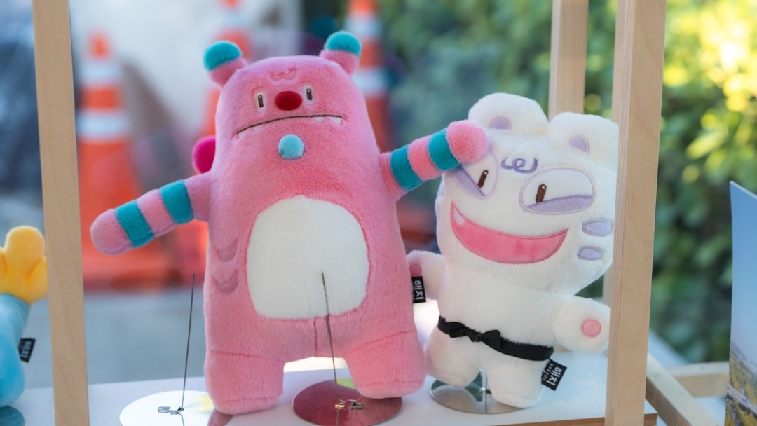 Two cartoon plush toys sit on a white wooden surface.