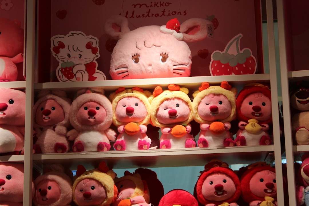 Pink and red plush toys arranged on retail store shelves.